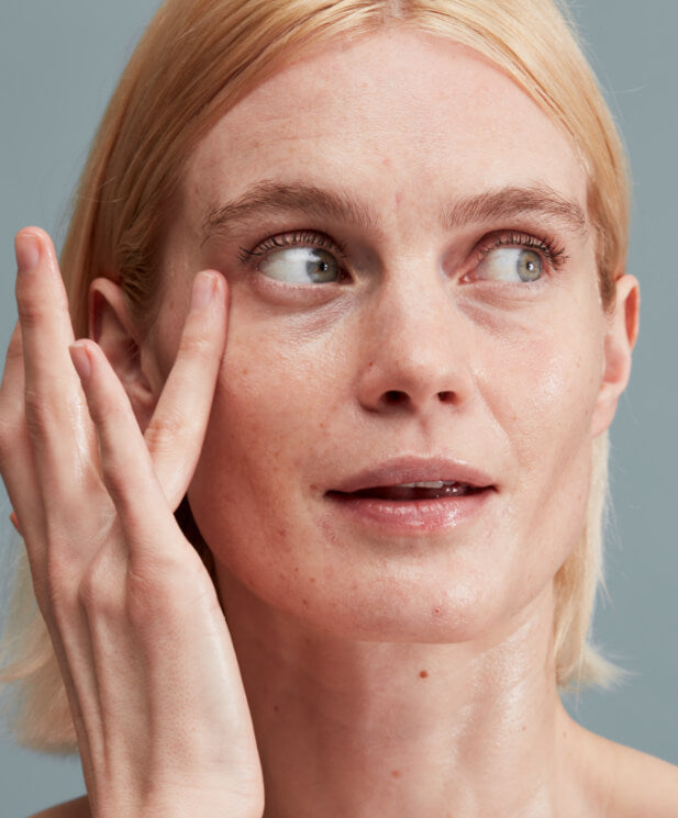 woman with bare skin touching her face