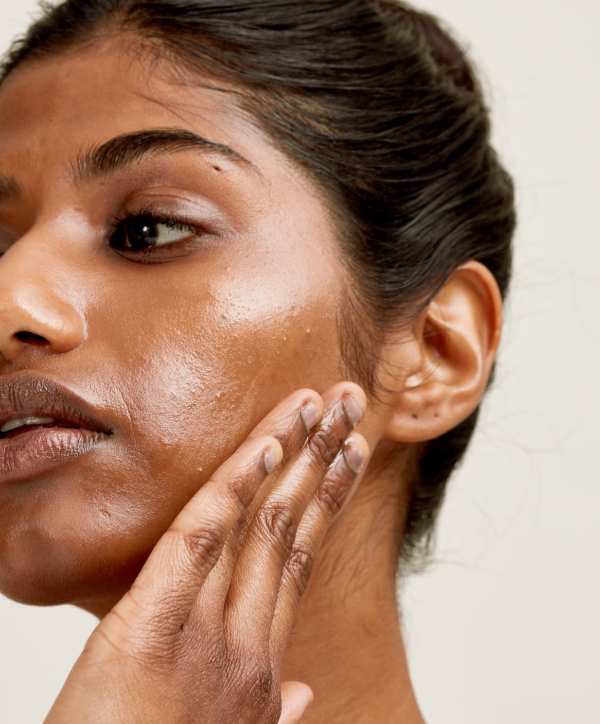 woman applying skincare to cheek